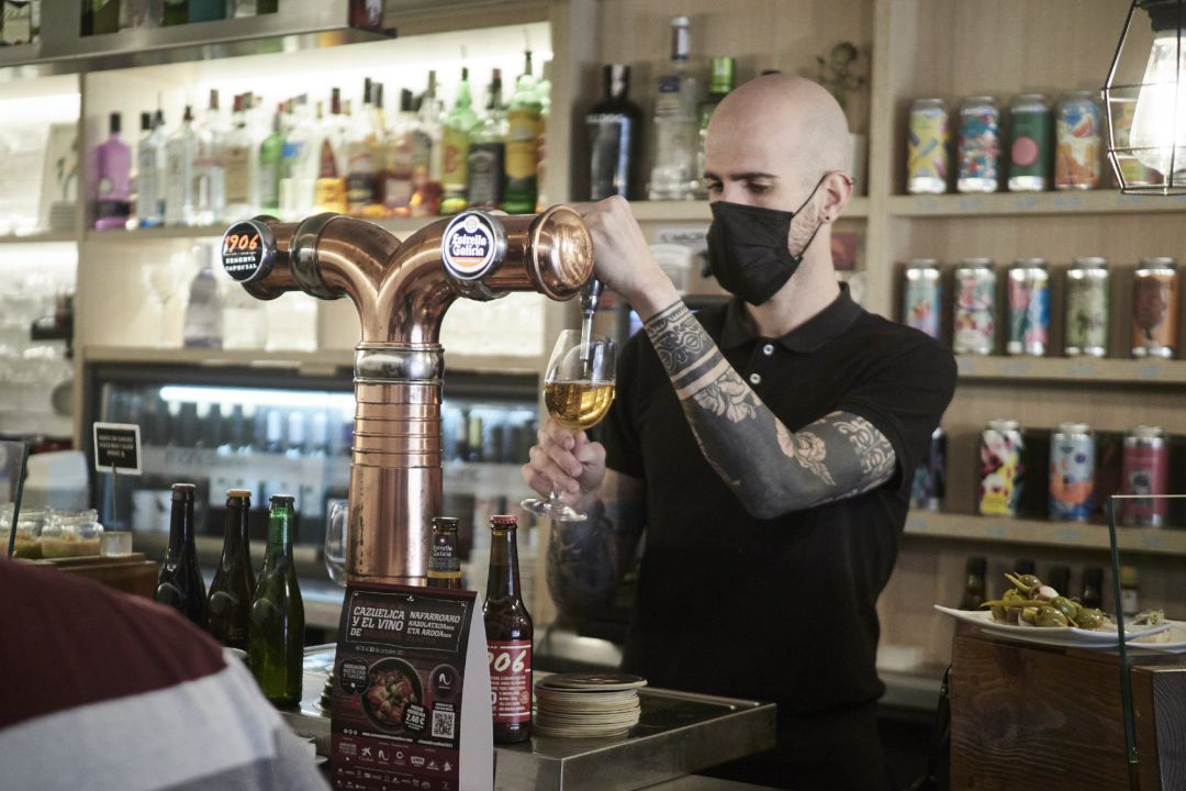 Archivo - Un camarero sirve una cerveza en el interior de un bar