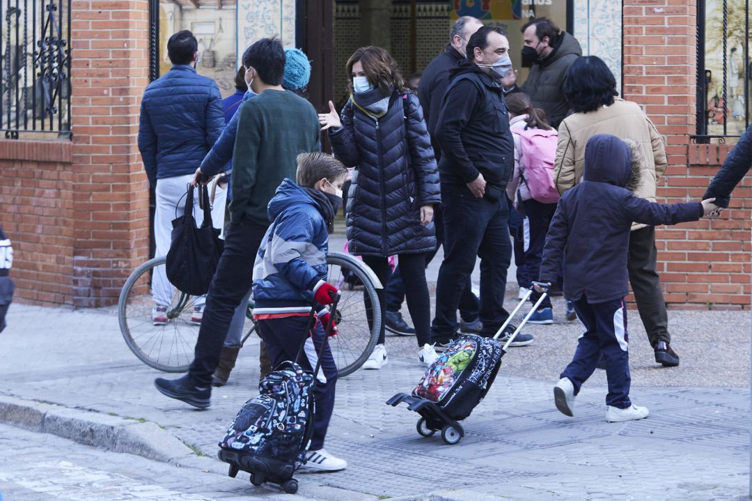 Unos niños cruzan un paso de peatones para entrar en el colegio durante la vuelta al colegio de los niños tras las vacaciones de Navidad con la aplicación de las nuevas restricciones